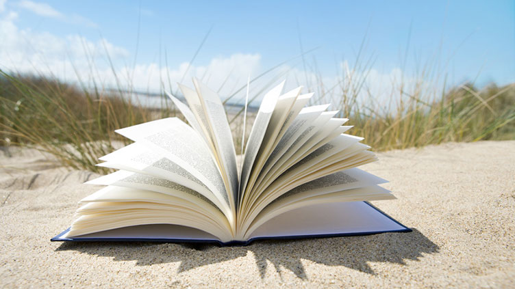 Ein aufgeklapptes Buch am Strand (Symbolbild für das Thema Vorlesen)