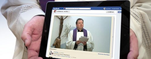 Pfarrer hält Tablet in seinen Händen. (Gottesdienste auch online)