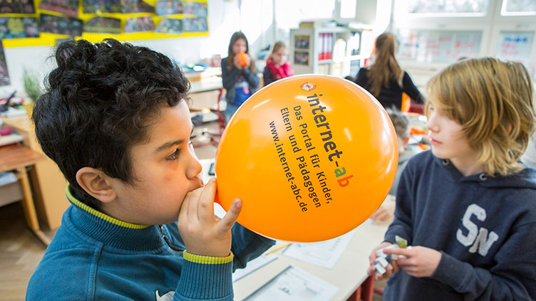 Kinder mit einem Luftballon mit der Aufschrift Internet-ABC